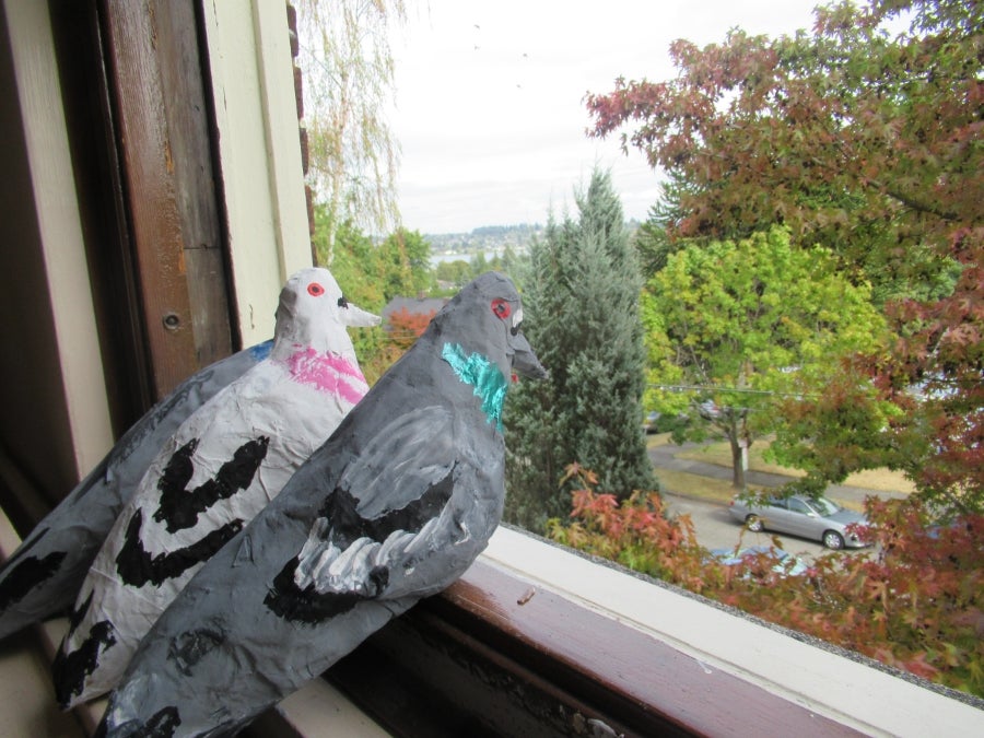 Paper Mache pigeons looking out a window